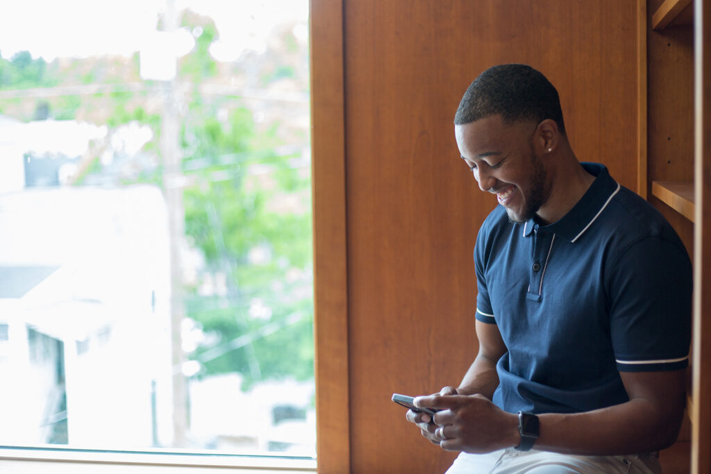 Designer smiling after receiving a job interview request on their phone